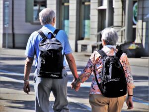 elderly couple walking hand in hand through town